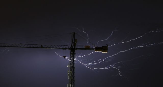 epa04390758 A picture made available on 08 September 2014 shows lightning behind a crane during a summer thunderstorm in San Sebastian, northern Spain, 07 September 2014.  EPA/JAVIER ETXEZARRETA