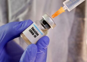 FILE PHOTO: A woman holds a small bottle labelled with a "Vaccine COVID-19" sticker and a medical syringe in this illustration taken April 10, 2020. REUTERS/Dado Ruvic/Illustration/File Photo