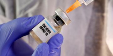 FILE PHOTO: A woman holds a small bottle labelled with a "Vaccine COVID-19" sticker and a medical syringe in this illustration taken April 10, 2020. REUTERS/Dado Ruvic/Illustration/File Photo