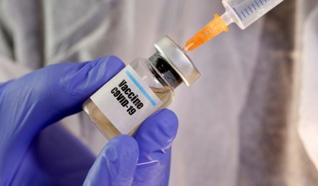 FILE PHOTO: A woman holds a small bottle labelled with a "Vaccine COVID-19" sticker and a medical syringe in this illustration taken April 10, 2020. REUTERS/Dado Ruvic/Illustration/File Photo