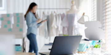 Digital tablet computer or laptop on home office desk with asia freelance seller woman happy packing check busy work in fashion studio SME online store social e-commerce sale page service web support.