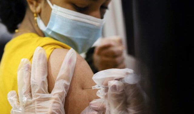 FILE PHOTO: A girl receives the Pfizer-BioNTech coronavirus disease (COVID-19) vaccine in Lansdale, Pennsylvania, U.S., December 5, 2021. REUTERS/Hannah Beier/File Photo