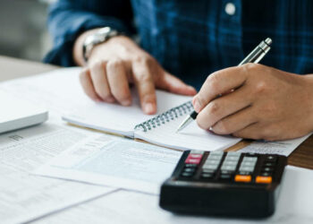 young man holding pen for fill out the document and take note to calculate business data, taxes, bills payment, Start up counting finance.accounting, statistics, and analytic research concept