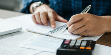 young man holding pen for fill out the document and take note to calculate business data, taxes, bills payment, Start up counting finance.accounting, statistics, and analytic research concept