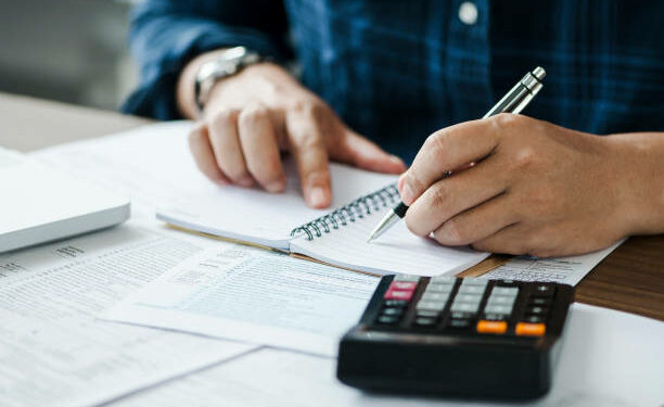 young man holding pen for fill out the document and take note to calculate business data, taxes, bills payment, Start up counting finance.accounting, statistics, and analytic research concept