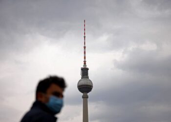 A person wearing a protective face mask walks nearby the TV tower at Alexanderplatz square after the German government loosened coronavirus (COVID-19) measures in Berlin, Germany, April 4, 2022. REUTERS/Lisi Niesner