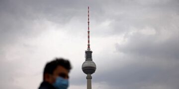 A person wearing a protective face mask walks nearby the TV tower at Alexanderplatz square after the German government loosened coronavirus (COVID-19) measures in Berlin, Germany, April 4, 2022. REUTERS/Lisi Niesner