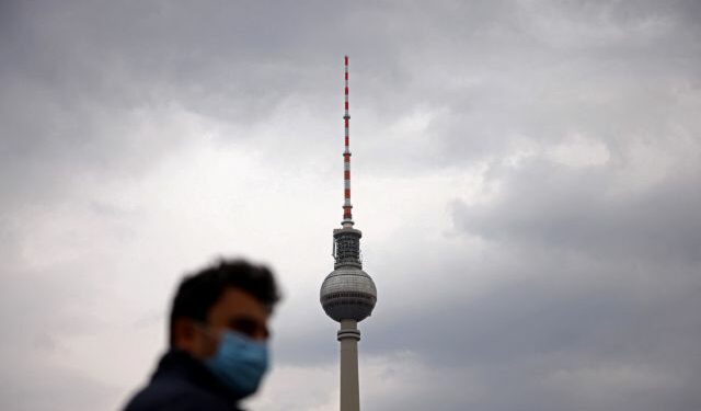 A person wearing a protective face mask walks nearby the TV tower at Alexanderplatz square after the German government loosened coronavirus (COVID-19) measures in Berlin, Germany, April 4, 2022. REUTERS/Lisi Niesner