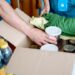 Volunteers Packing humanitarian aid in donation box. Group of unrecognizable people working in charitable foundation helping in crises and homeless.Donation and charity concept