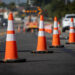 Traffic cones on road with electronic arrow pointing to the right to divert traffic and white car in distance