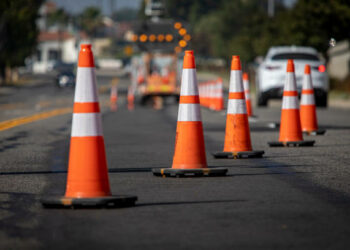 Traffic cones on road with electronic arrow pointing to the right to divert traffic and white car in distance
