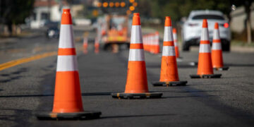 Traffic cones on road with electronic arrow pointing to the right to divert traffic and white car in distance